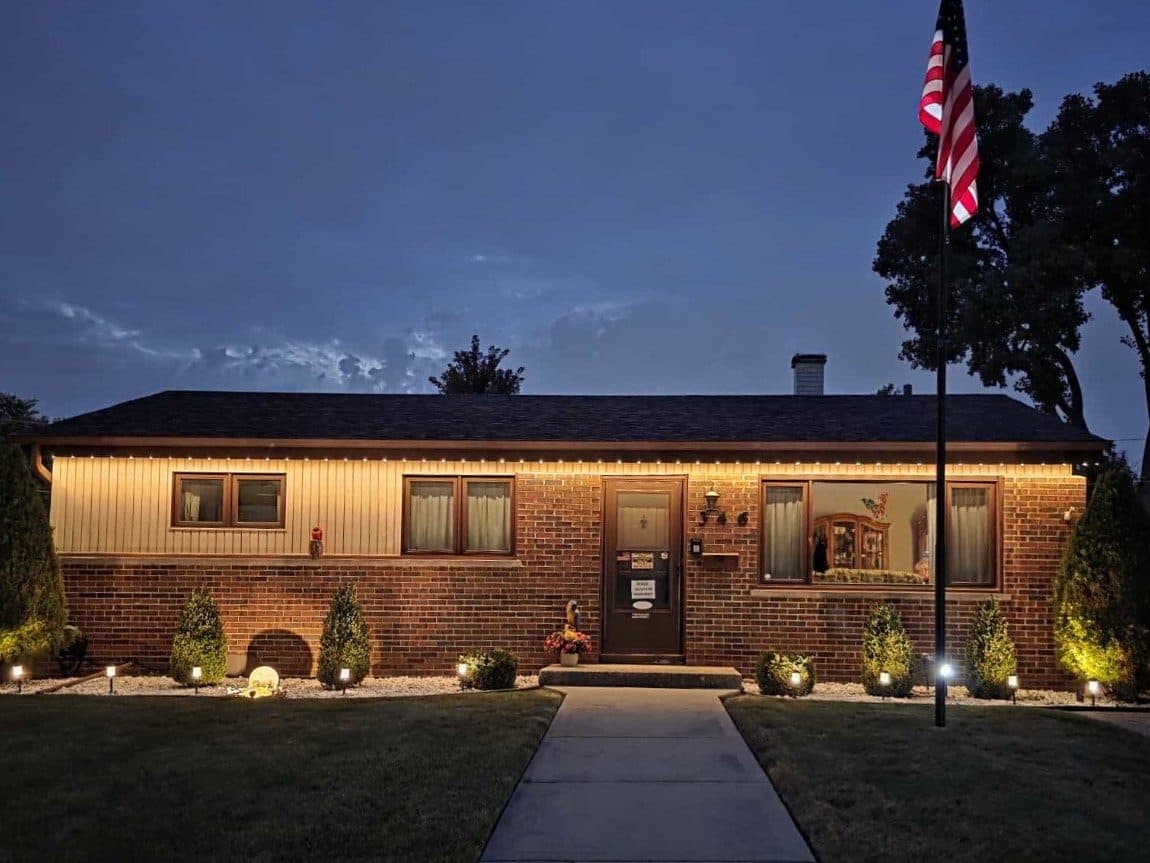 Classic brick ranch home in Elgin, IL with permanent exterior lighting along the roofline