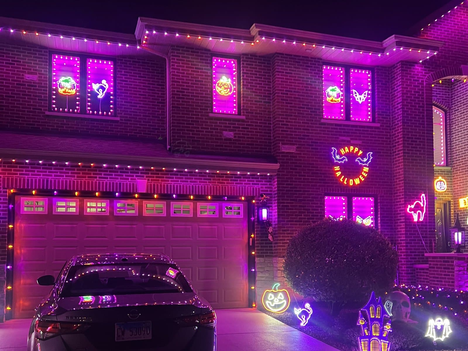 Brick two-story home in Tinley Park, IL with permanent lighting set to a purple and orange Halloween scene