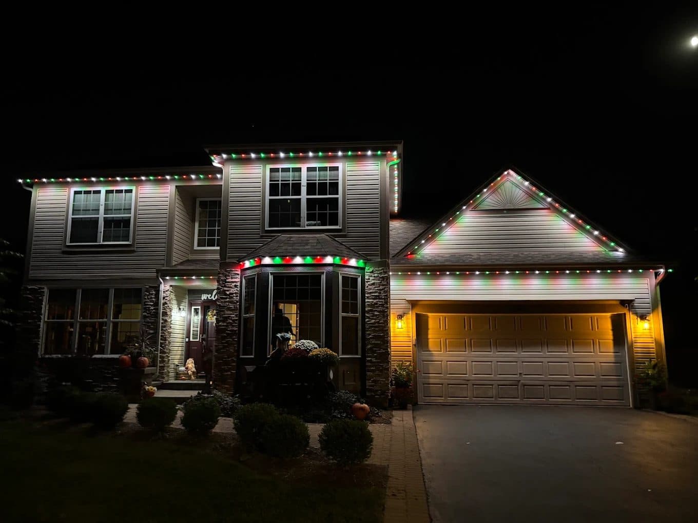 Two-story home in Sugar Grove, IL with permanent lighting set to a red and green Christmas scene