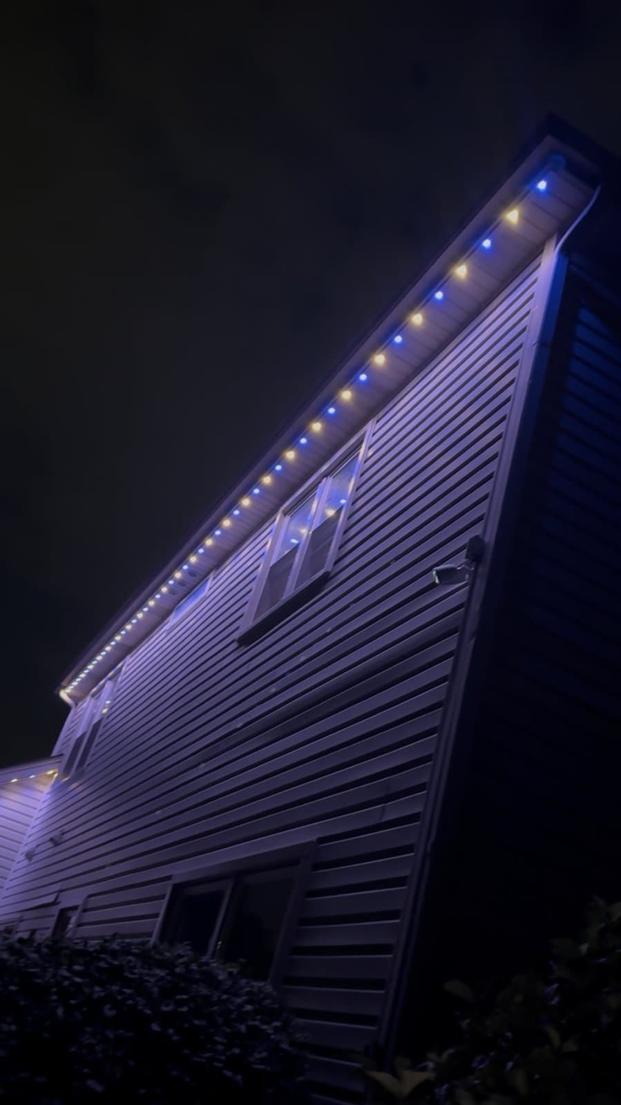 Close-up of a gable roofline alternating warm white and blue lights